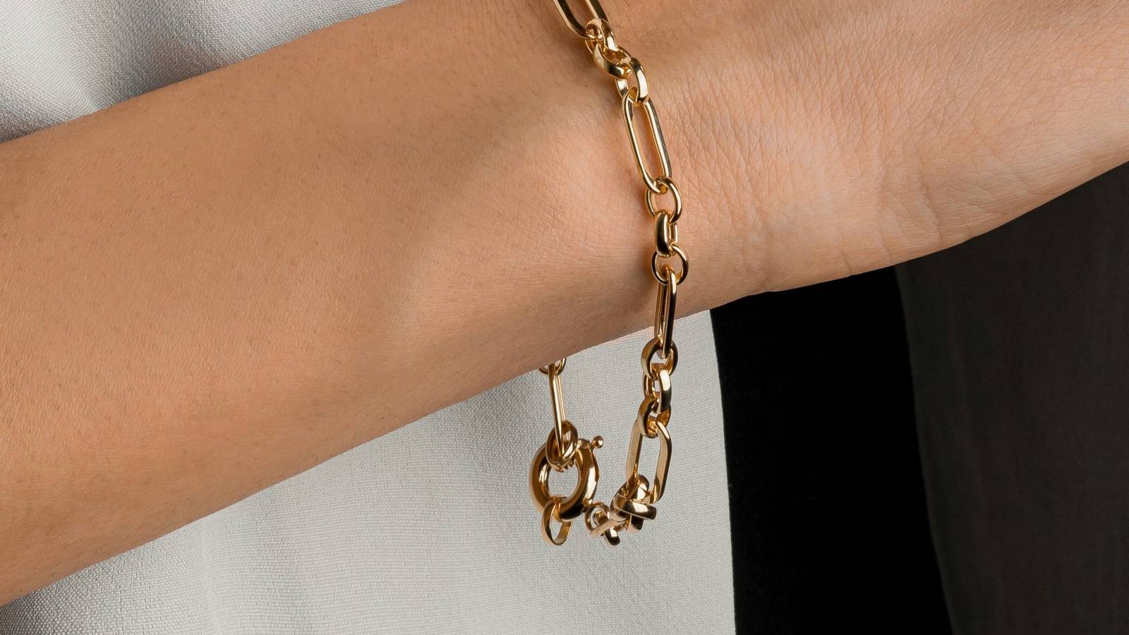 Wrist wearing a gold chain bracelet
